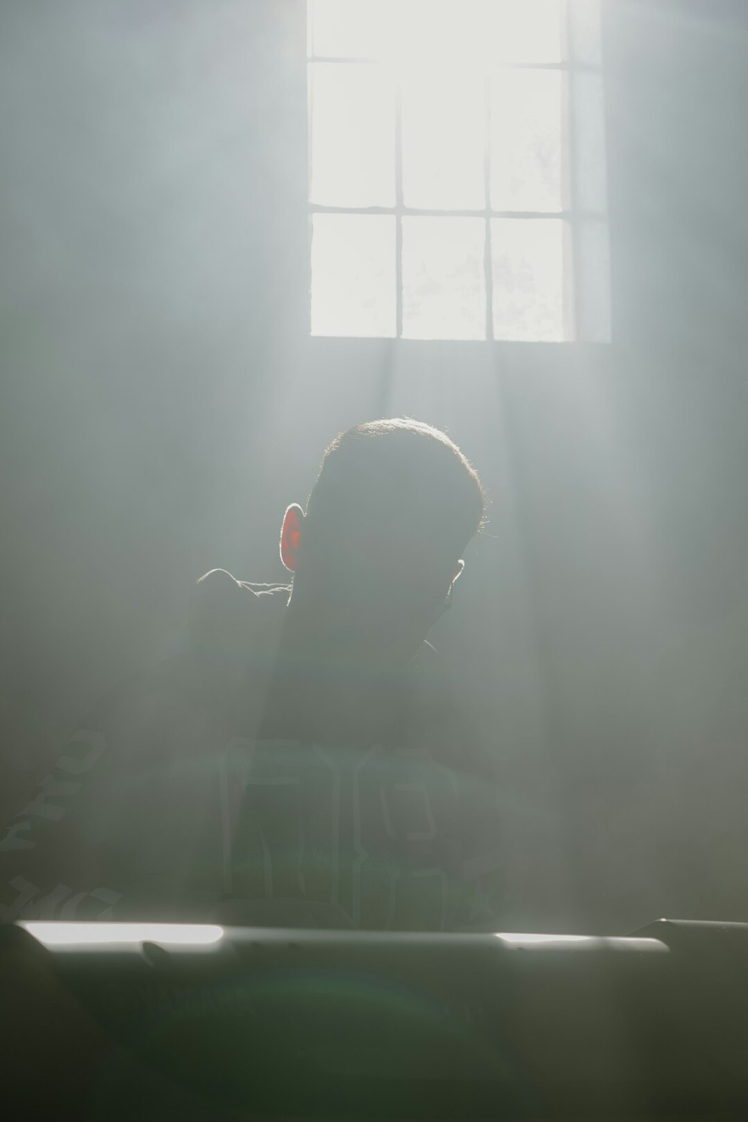 Person meditating peacefully by a window in soft morning light