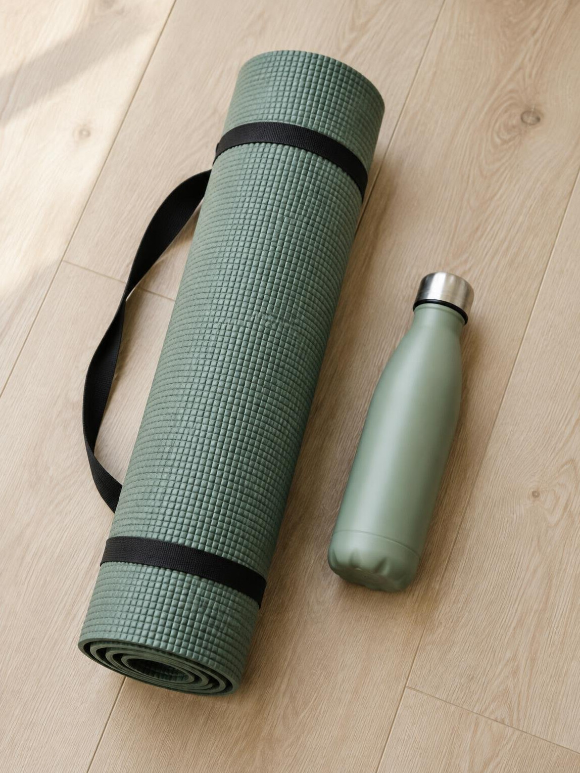 Rolled yoga mat and water bottle on a wooden floor